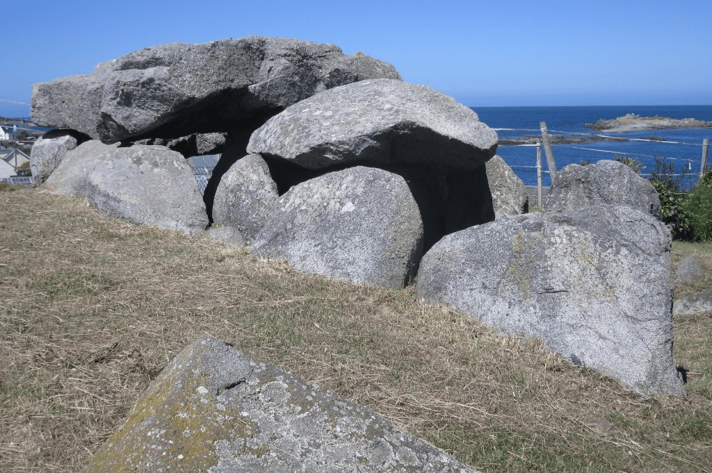A Channel Islands megalithic dolmen of weathered Guernsey granite above the sea.